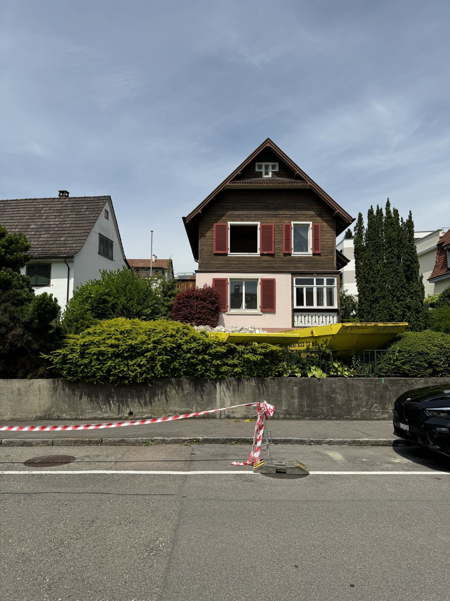 Bestand vor dem Umbau, Einfamilienhaus mit dunkler Holzfassade und roten Fensterläden