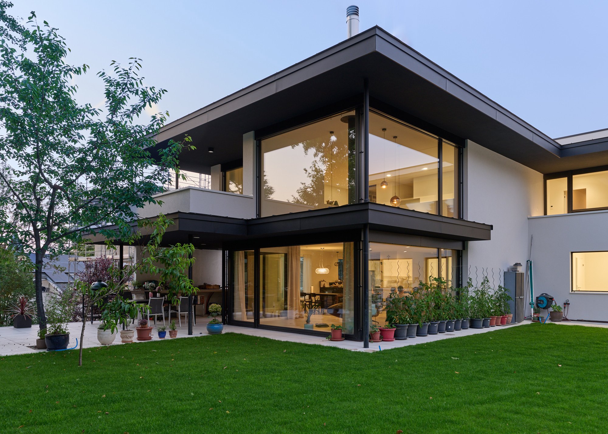 Gartenseite mit raumhoher Eckverglasung am Abend